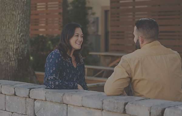 man and woman having pleasant conversation by stone wall