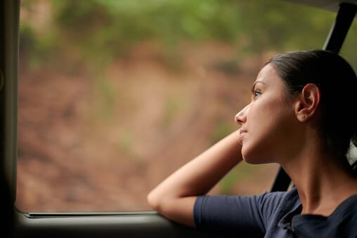 young woman staring out of car window contemplating the effects of alcohol