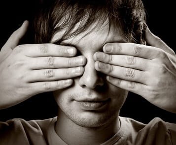 black and white closeup of young man with fingers covering his eyes