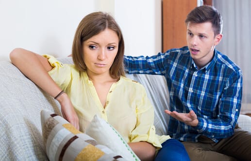 man on couch having discussion about opioids with woman who has turned away from him
