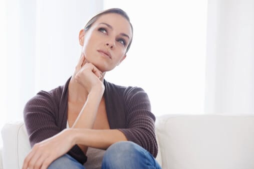woman on couch looking into distance with finger under chin contemplating questions to ask