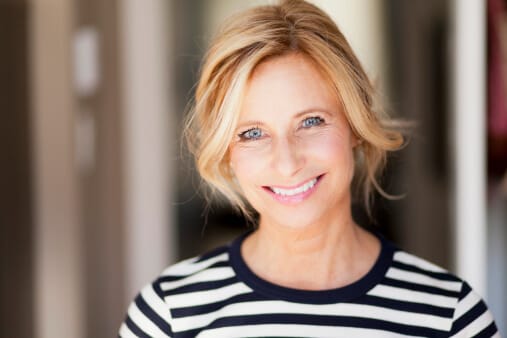 blonde woman in striped shirt with smiling eyes contemplating recovery
