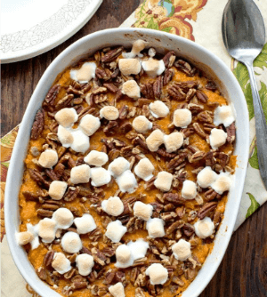 sweet potato and pumpkin casserole with marshmallows and pecans in a baking dish on the table