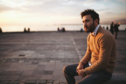 young man in sweater on pier contemplating why alcohol is addictive