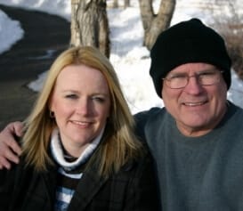 an older man in a stocking cap with his arm around his adult daughter