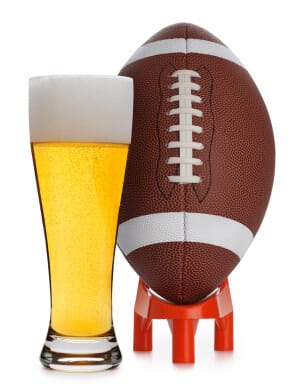 football on a tee sitting next to a glass of beer