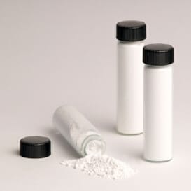 three vials of the white powder known as bath salts one of which is tipped over with its contents spilling on the table