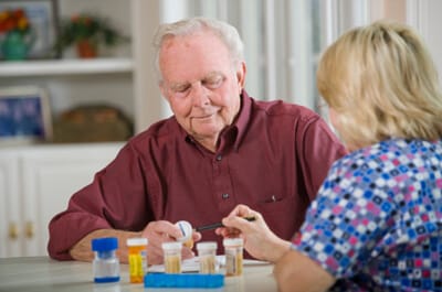 nurse explaining prescriptions drugs to elderly man