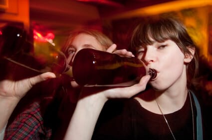 two female college students drinking beer from bottles