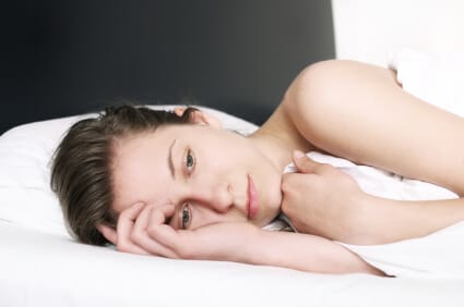 worried woman lying on her side in bed unable to sleep