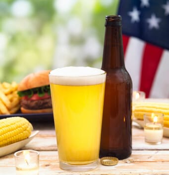 glass of beer and beer bottle with barbecue and american flag