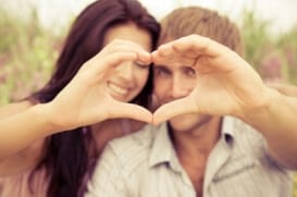 a man and woman in recovery smiling and forming their two hands into a heart symbol