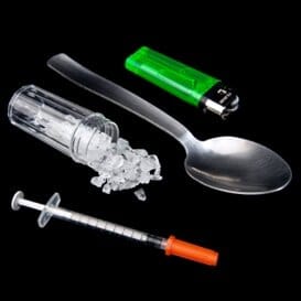 a picture of a syringe a vial of methamphetamine a spoon and a disposable lighter on a black background