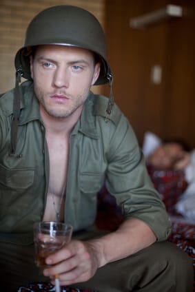 man in military fatigues with drink and cigarette