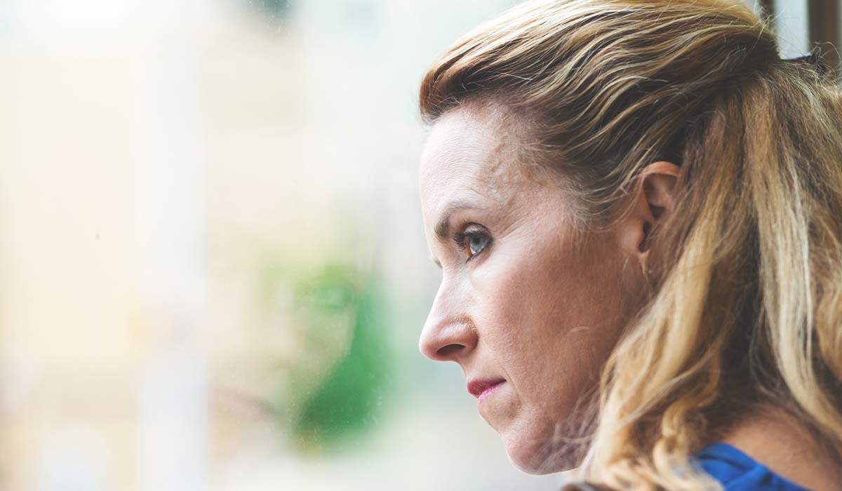 contemplative woman staring out of window with reflection
