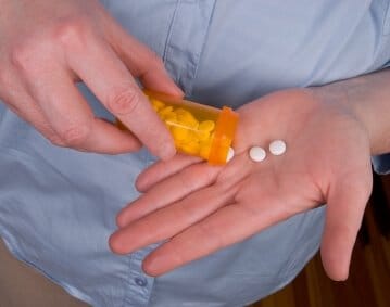 closeup of person pouring pills from prescription bottle into upturned palm