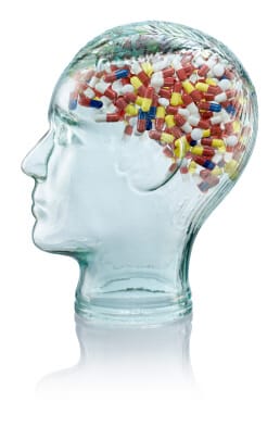 glass model of human head with pills where brain should be