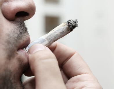 closeup of young man smoking marijuana joint