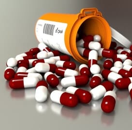 tipped over prescription bottle with red and white capsules spilling out illustrating the anatomy of pain and addiction to prescription pain killers