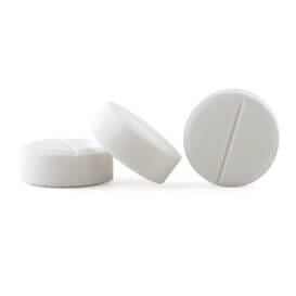 close up of three small white tablets leaning against each other