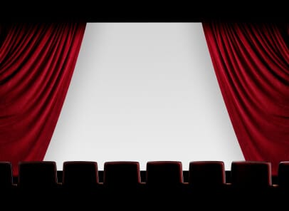 view from the balcony at a movie theater with a red curtain being drawn to reveal a movie screen